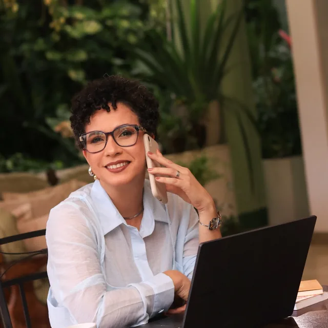 Nai Moraes ao telefone, em frente ao notebook